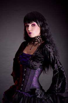 Portrait of attractive gothic girl in elegant medieval costume, studio shot on black background 