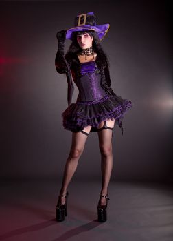 Sexy witch in purple and black fantasy Halloween costume, full length shot  