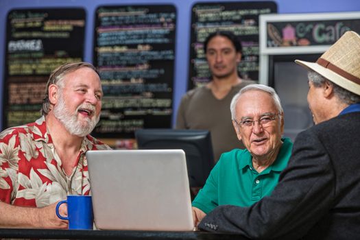 Laughing people in a coffee house with laptop