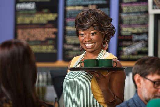 Beautiful Black woman in apron serving drinks on a tray
