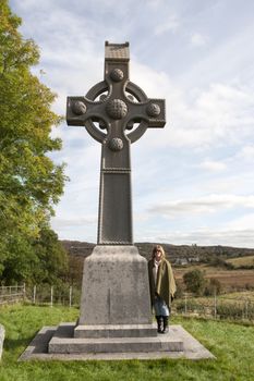 female tourist at memorial celtic cross in honor of saint colomba founder of the colomban monks