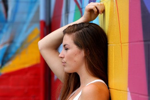 Side view portrait of a woman with colorful wall in the background.
