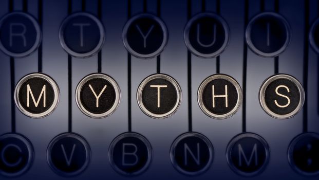 Close up of old manual typewriter keyboard with scratched chrome keys that spell out "MYTHS".  Lighting and focus are centered on "MYTHS". 