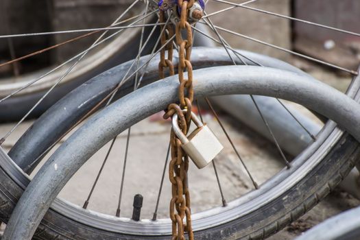 Lock and chain on a bicycle ,Close up view of a large lock and chain attached to an old bicycle parked .