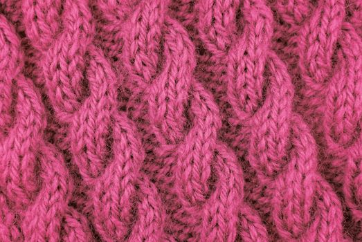 Closeup of pink coiled rope cable stitch knitting on the diagonal