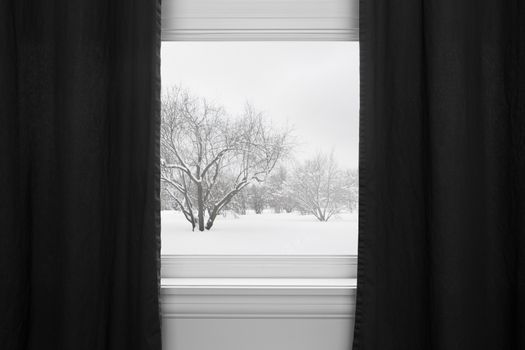 Winter landscape seen through the window with black curtains.