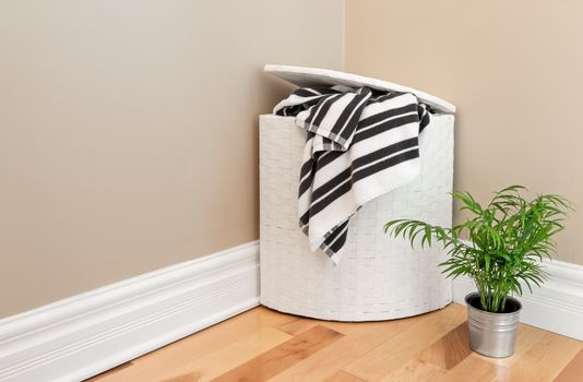 Laundry basket with striped towels and green plant in the room corner.