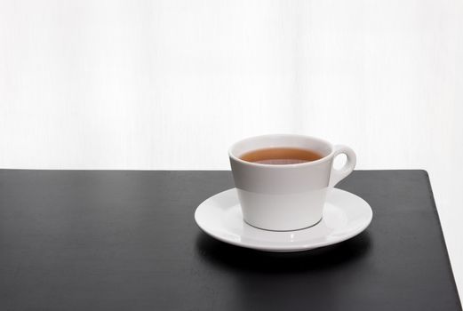 Cup of tea on a black table, on white background.