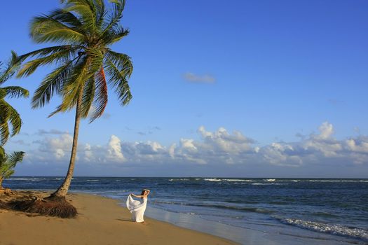 Young woman in white dress on a beach