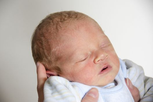 Cute baby sleeping in the hands of its mother with open mouth