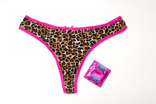 Bright coloured knickers with a wrapped condom on white background