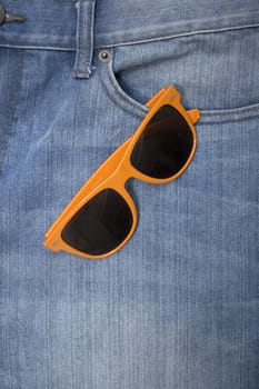 Orange sunglasses in a denim jeans pocket