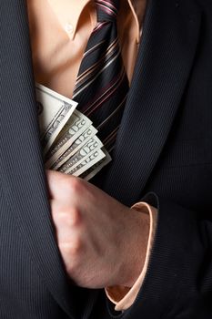 Close up of a business mans hand hiding money in his suit jacket pocket.