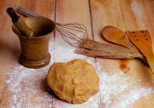 Arrangement of Dough, Kitchen Utensils, Bronze Mortar and Pestle with Flour on Wooden background