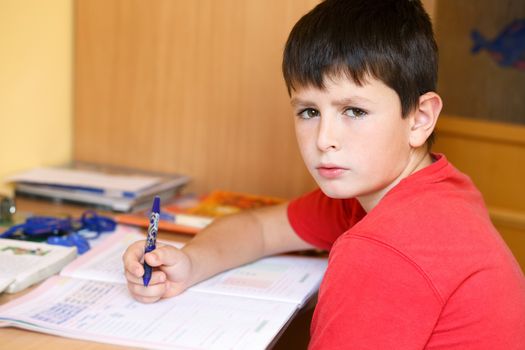 boy doing school homework, is tired and bored