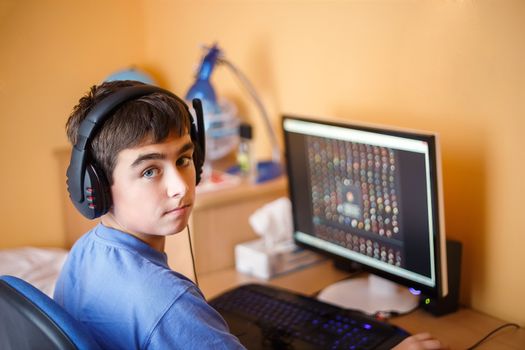 Teenager using computer at home, play game in his child room