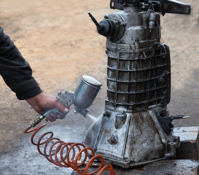 Repairing a car with his hands. Cleaning  gearbox via a special liquid sprayed under pressure