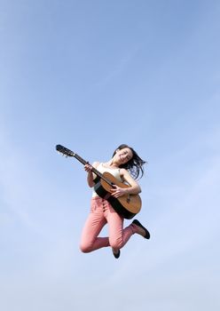 happy young woman jumping with guitar