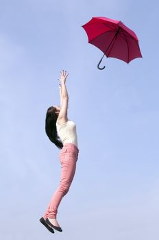 young woman jumping with red umbrella