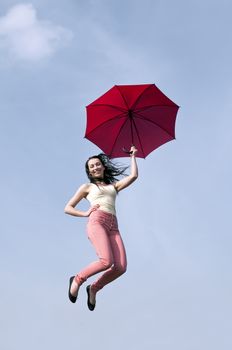 young woman jumping with red umbrella