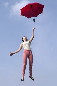 young woman jumping with red umbrella