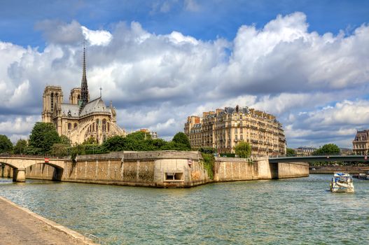 Famous Notre Dame de Paris Cathedral under beautiful cloudy sky in Paris, France (view from Seine river).