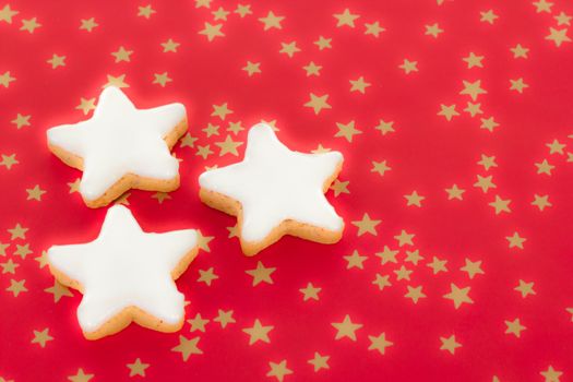 Shining star shaped cinnamon biscuits on red background with golden stars