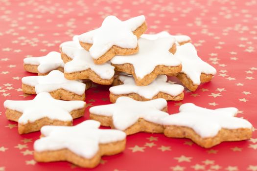Many star shaped cinnamon biscuits on red background with golden stars