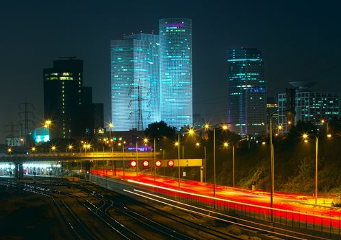 Night view of Tel Aviv city downtown, illuminated Azrieli towers and light traces on Ayalon highway.