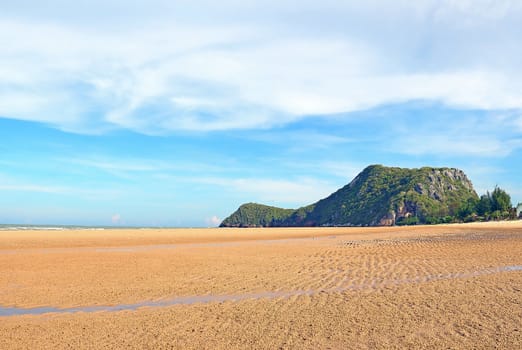 Beach sand with the mountain and blue sky background, at the Pranburi sea in Thailand