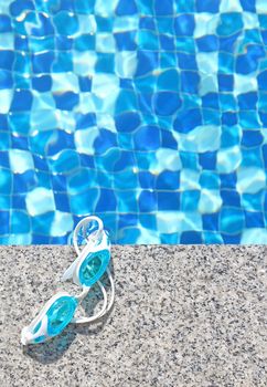 Blue swimming goggles on swimming pool background