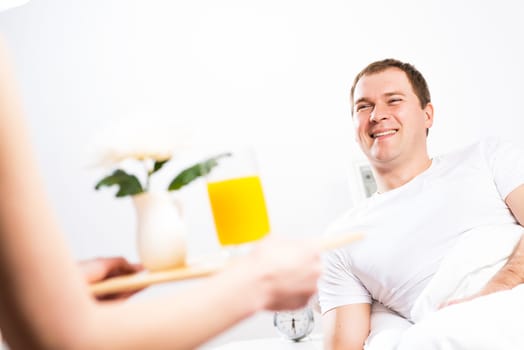 woman brought her boyfriend breakfast in bed, holding a tray of juice and breakfast