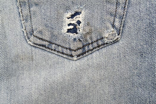 Close up image of denim jeans pocket with a ripped hole