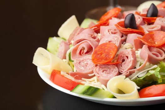 A delicious looking tossed chefs salad or antipasto with meat cheese and kalamata olives.