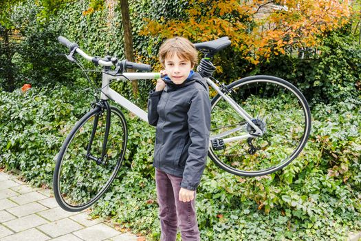 young boy carrying his bike