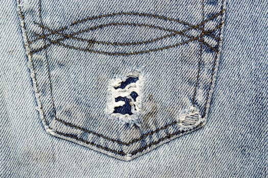 Close up image of denim jeans pocket with a ripped hole