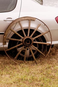 old broken wagon wheel side by new cars back