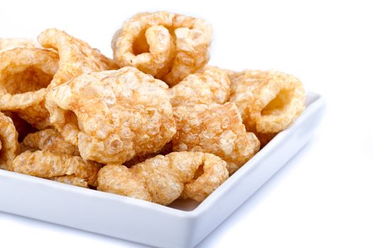 Pork rinds on white dish on white background