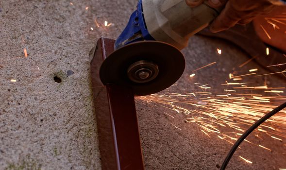 Metal sawing with hand grinder. Sparks while grinding iron.