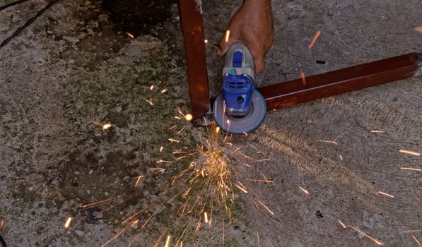 Metal buffing with hand grinder. Sparks while grinding iron.