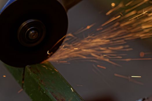 Metal sawing with hand grinder. Sparks while grinding iron.