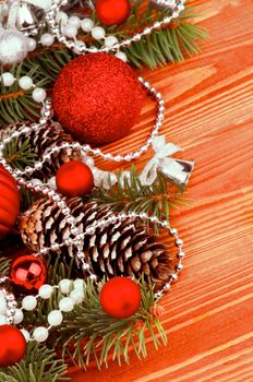 Arrangement of Spruce Branch and Fir Cones with Red and Silver Baubles, Bows,  Pearl and Silver Beads closeup on Wooden background