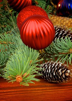 Christmas Decoration with Spruce Branch, Red Bauble and Fir Cones closeup on Wooden background