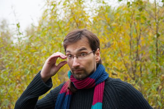 man with glasses on a background of autumn forest