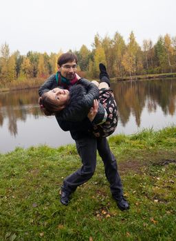 man turns a woman on the hands on the nature near the lake