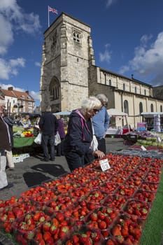 Buying strawberries on a market stall in the market town of Malton in North Yorkshire in the United Kingdom.