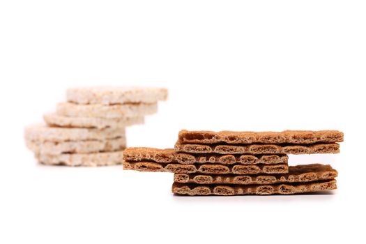 Two stacks. Puffed rice snack and grain crisp bread. White background.