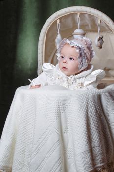 Cheerful and happy blue-eyed baby in  bonnet lies in cradle