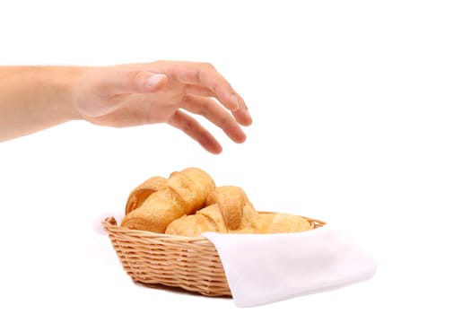 Hand reaches for the croissants in a basket. White background.