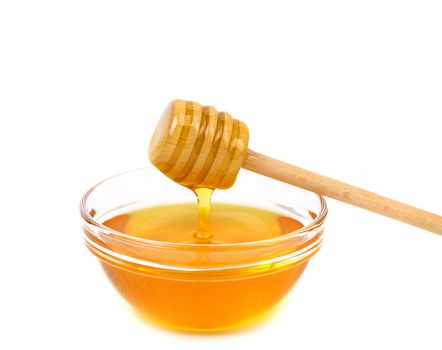 Honey dripping from a wooden honey dipper on white background